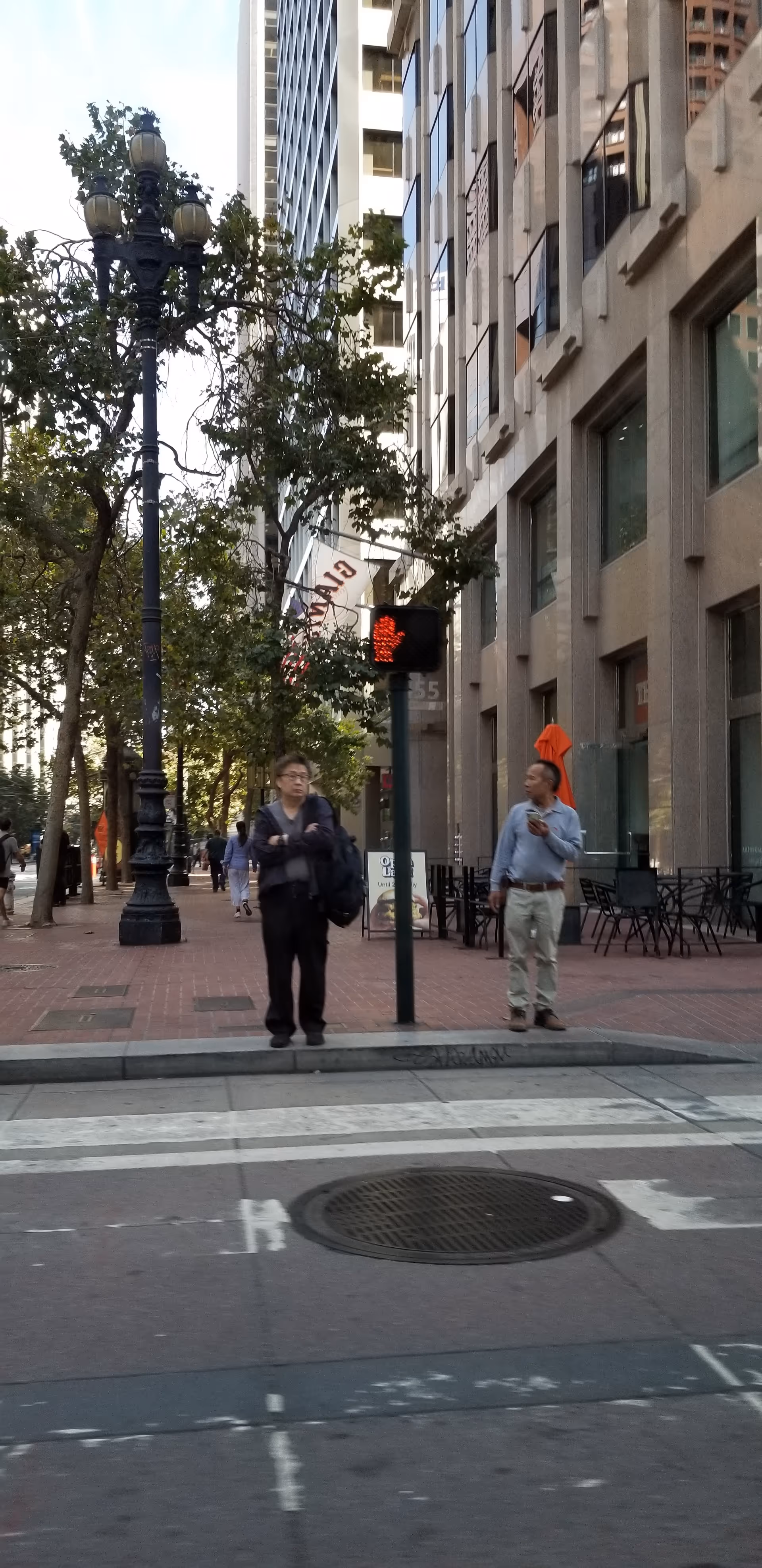 Urban sidewalk scene with two men standing near a storefront on a city street.