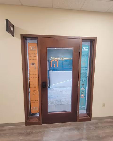 Doorway with glass panels displays Right at Home banners inside a hallway.