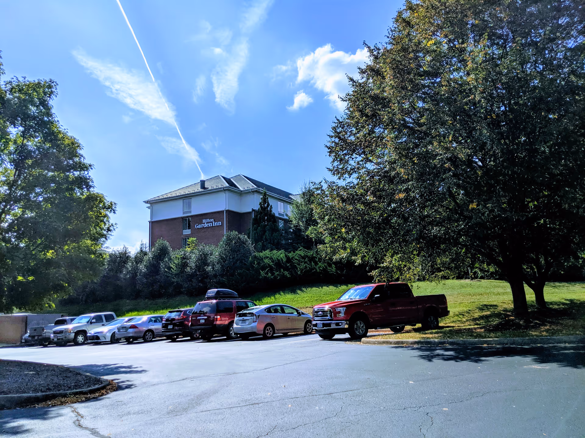 Exterior view of a brick building with a parking lot and surrounding trees.
