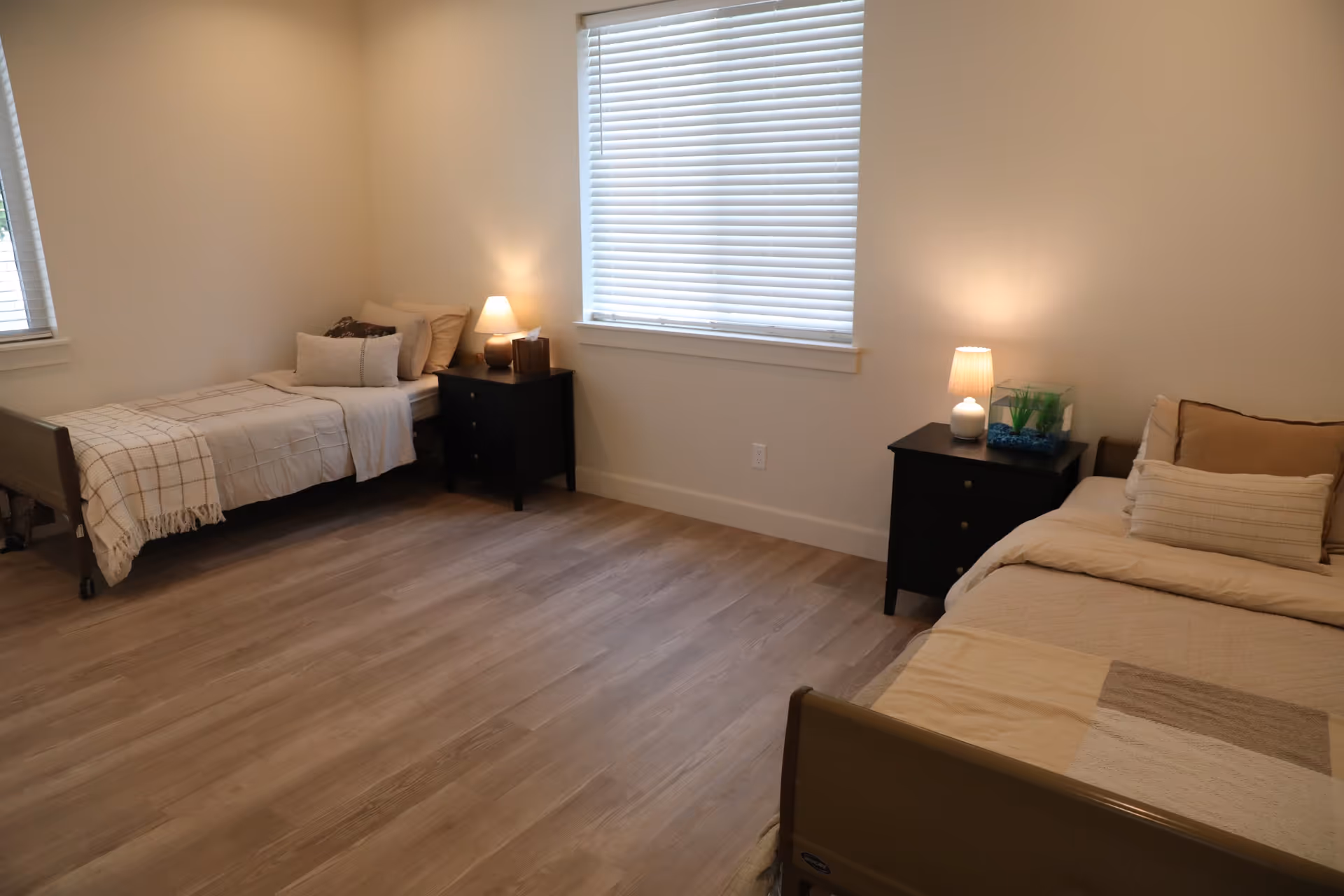Two single beds with nightstands and lamps in a tidy neutral-colored bedroom.
