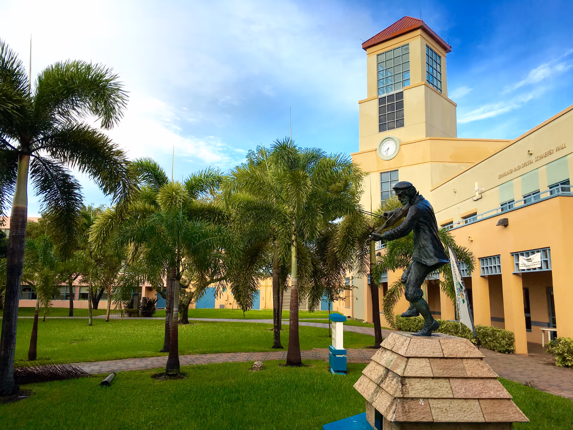 Exterior view of Miami Jewish Health building with palm trees and a statue in front.