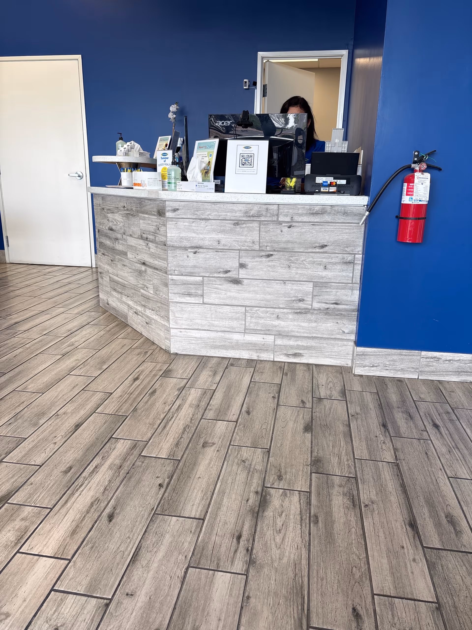 Reception desk in blue interior lobby with computer and supplies.