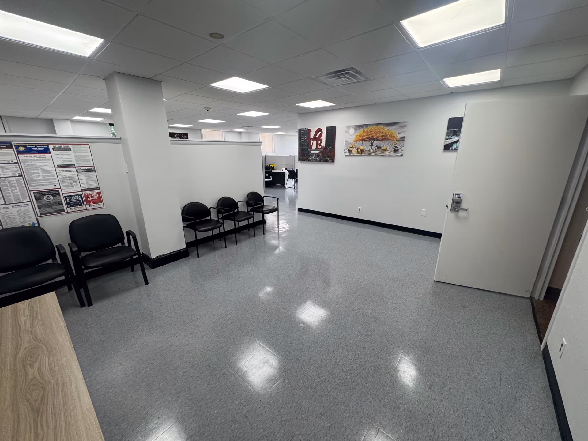 A spacious facility lobby with black chairs along walls and posters on white walls.