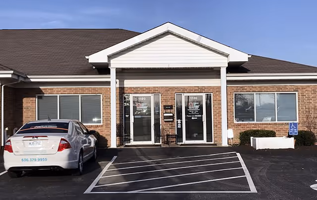 Exterior view of Right at Home facility entrance with brick facade and a parked car.