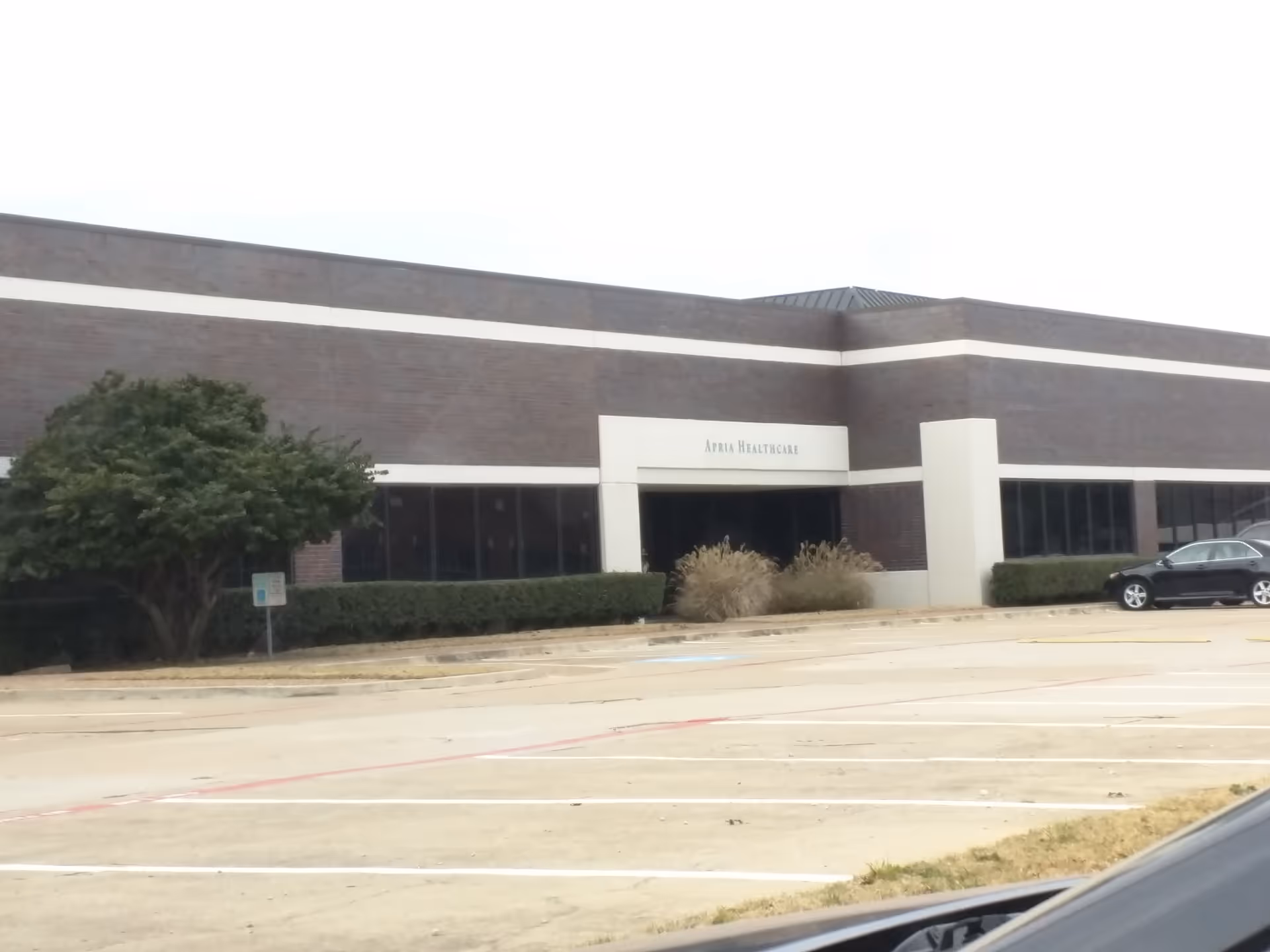 Exterior view of a brick healthcare facility with a parking lot in front.