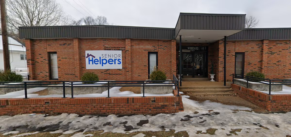 Brick senior living facility exterior with entrance and Senior Helpers sign.