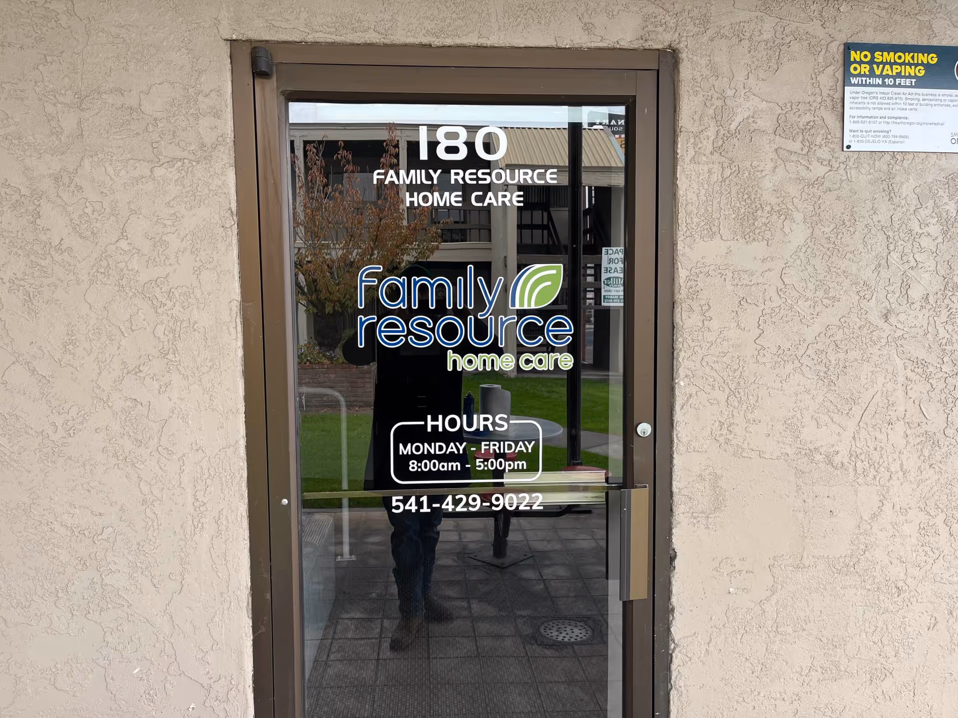 Glass entrance door with Family Resource Home Care signage and hours on beige stucco wall.