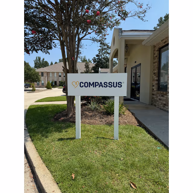 Exterior view of a Compassus building with a front sign and entrance.