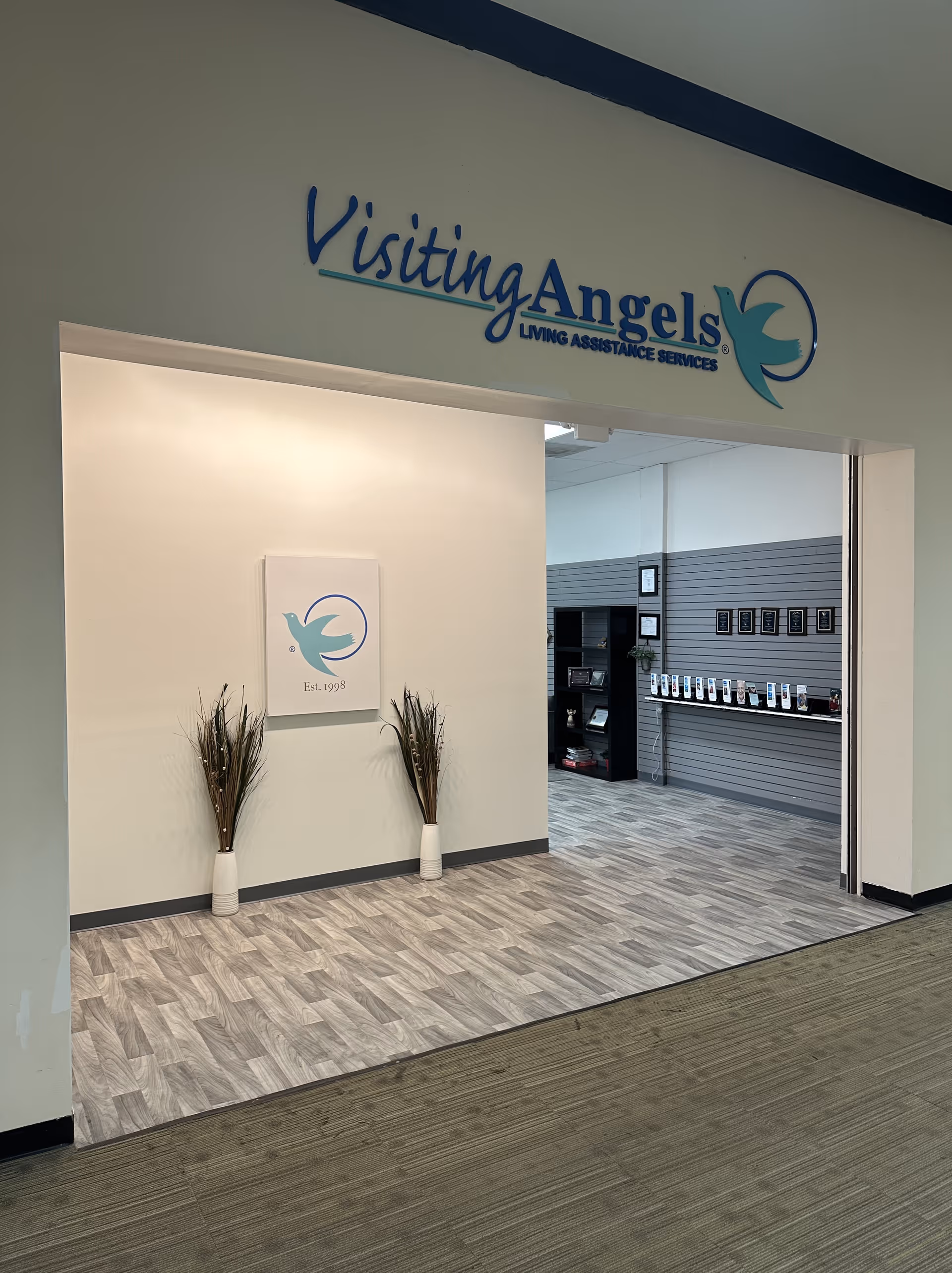 Entrance lobby of Visiting Angels with sign, logo, and decorative plants inside.