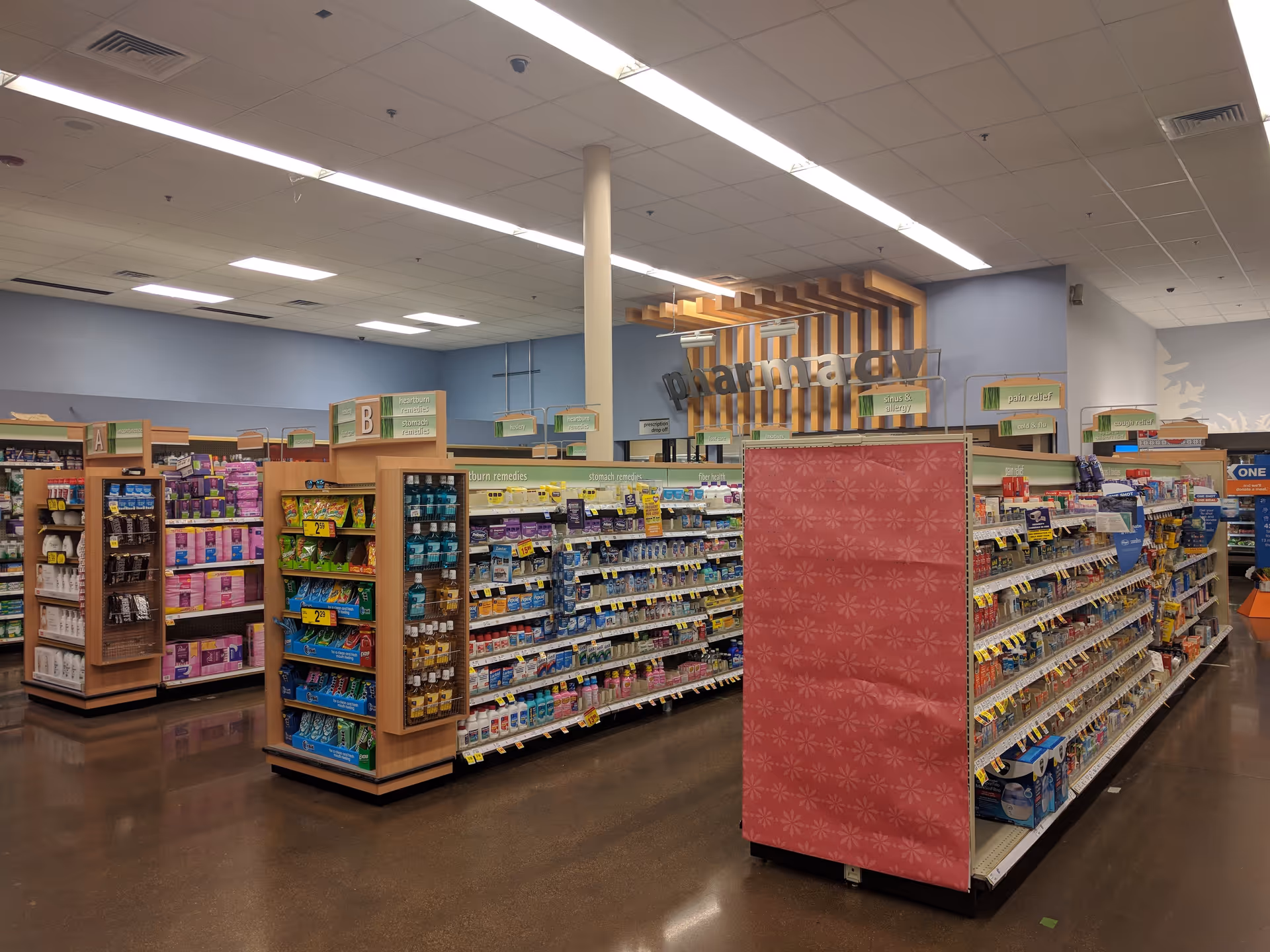Inside a Kroger Pharmacy aisle with stocked medication shelves and signage