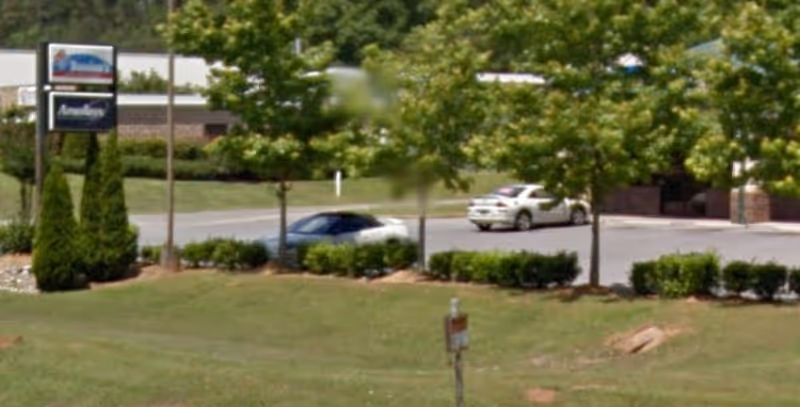 Exterior view of Amedisys Home Health Care facility entrance with signage and cars.
