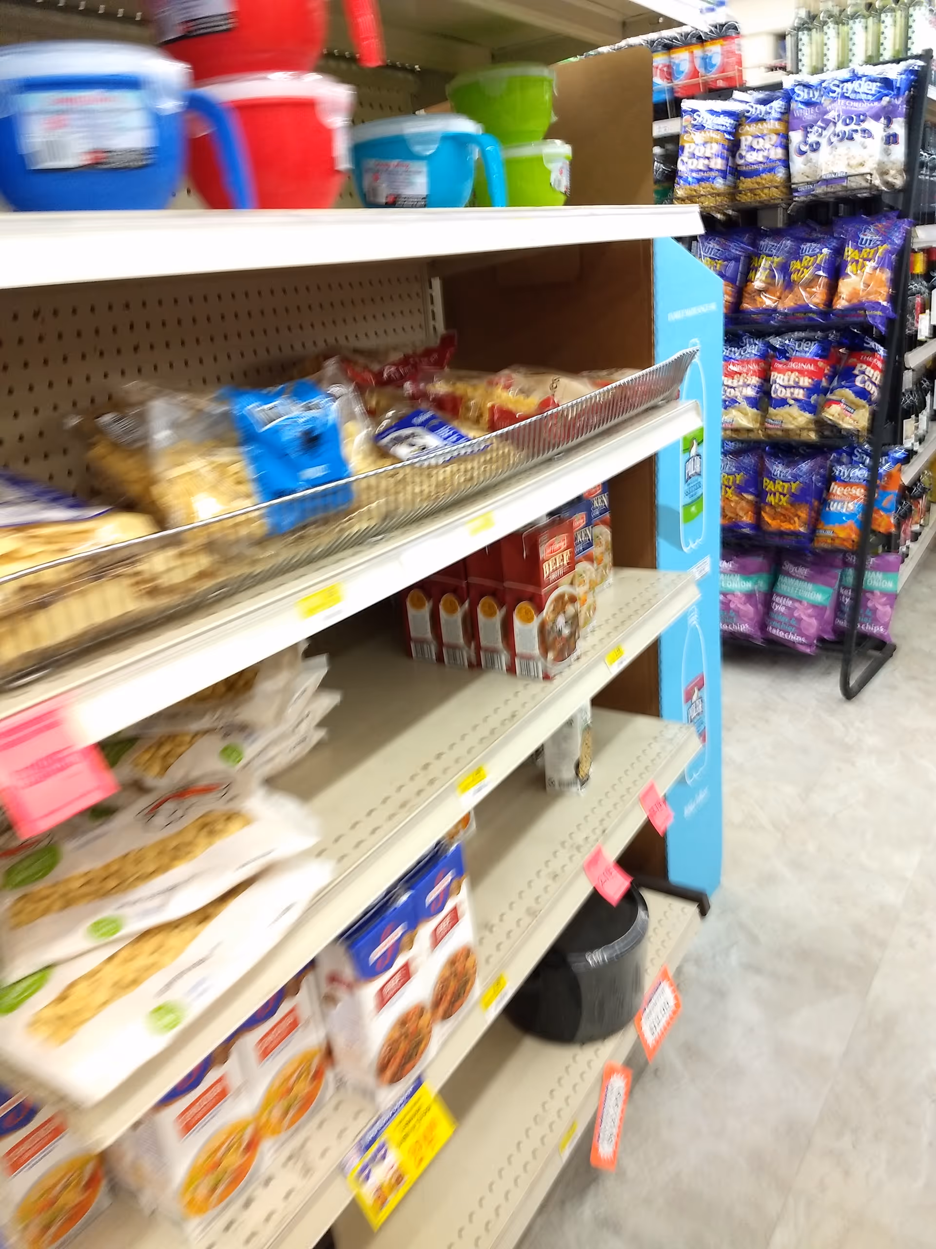 Store aisle with snacks and pet food on shelves.