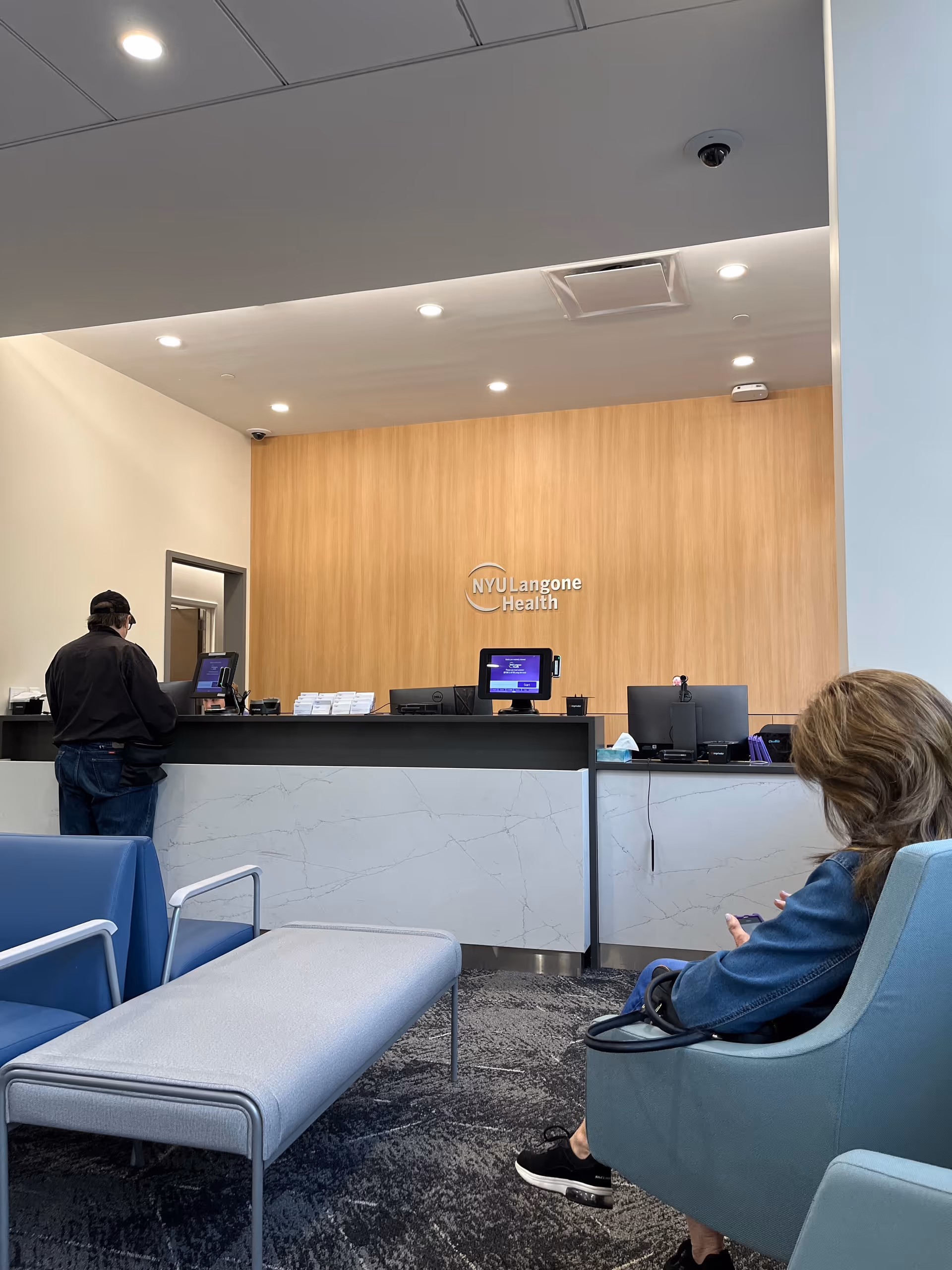 Lobby reception area featuring NYU Langone Health logo and blue seating.