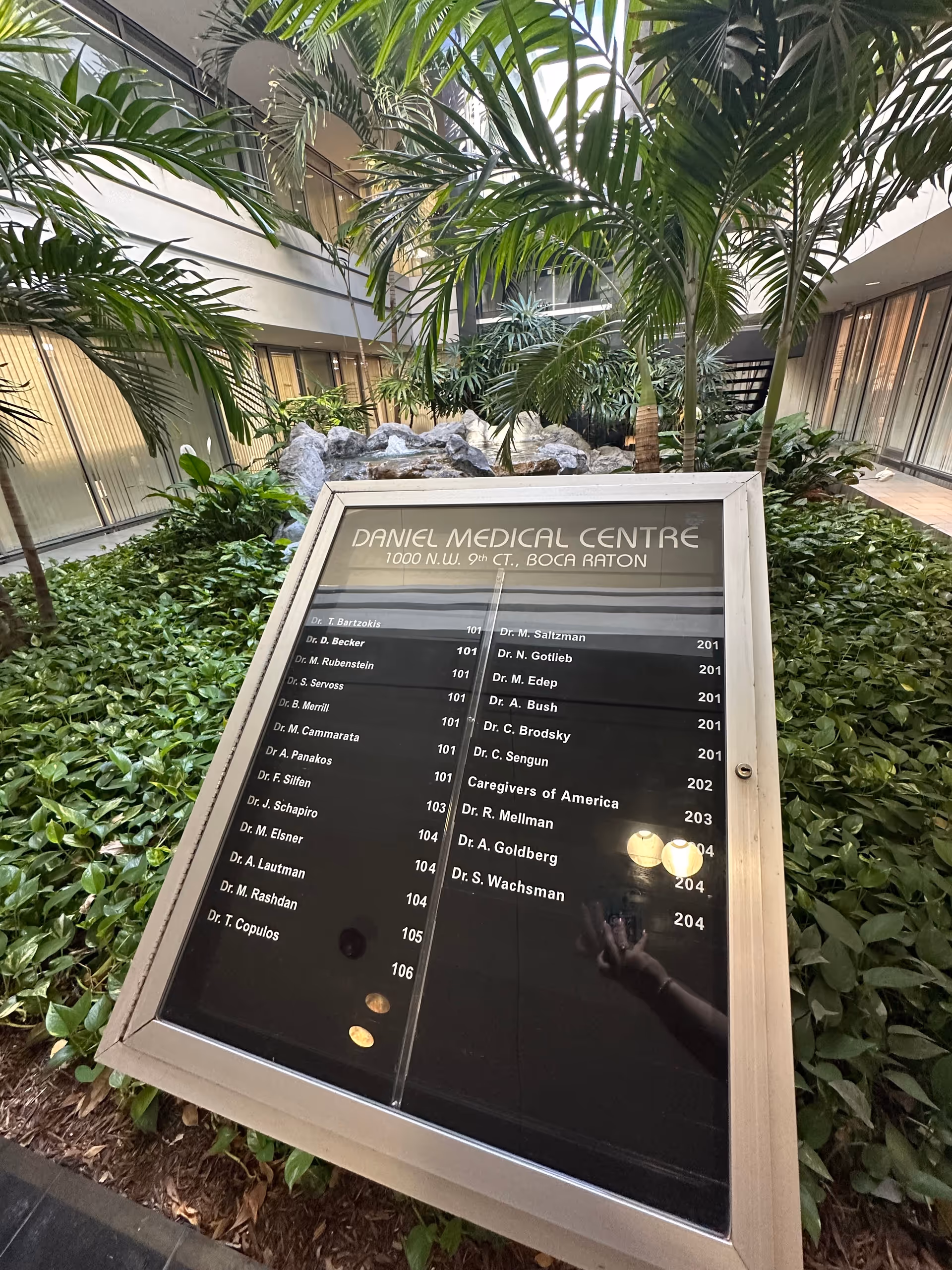 Indoor atrium filled with tropical plants and a large directory sign.