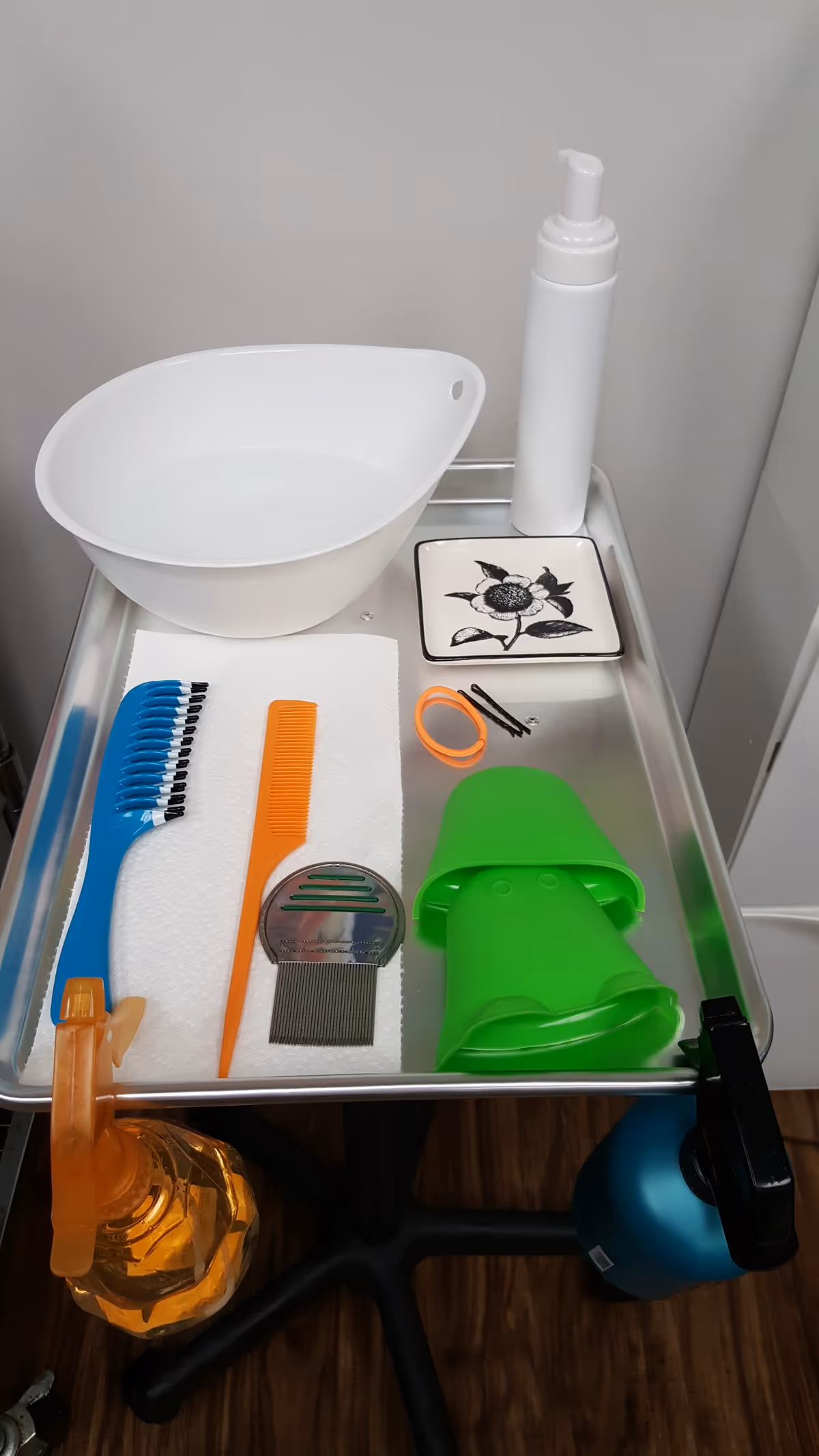 A metal rolling cart with a white basin and grooming tools in a clinical interior.