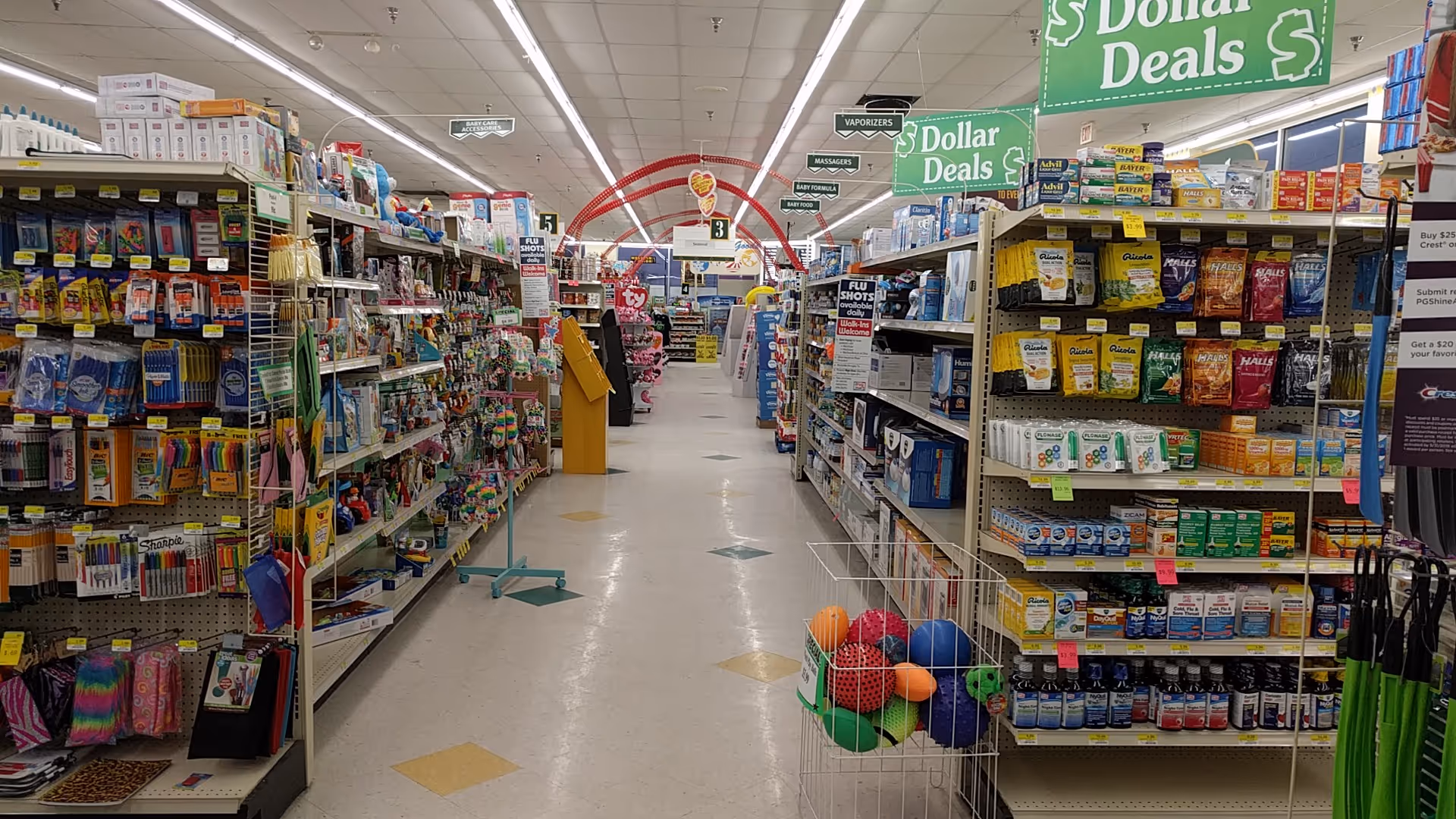 Inside a Discount Drug Mart store, aisles stocked with items and dollar deal signs.