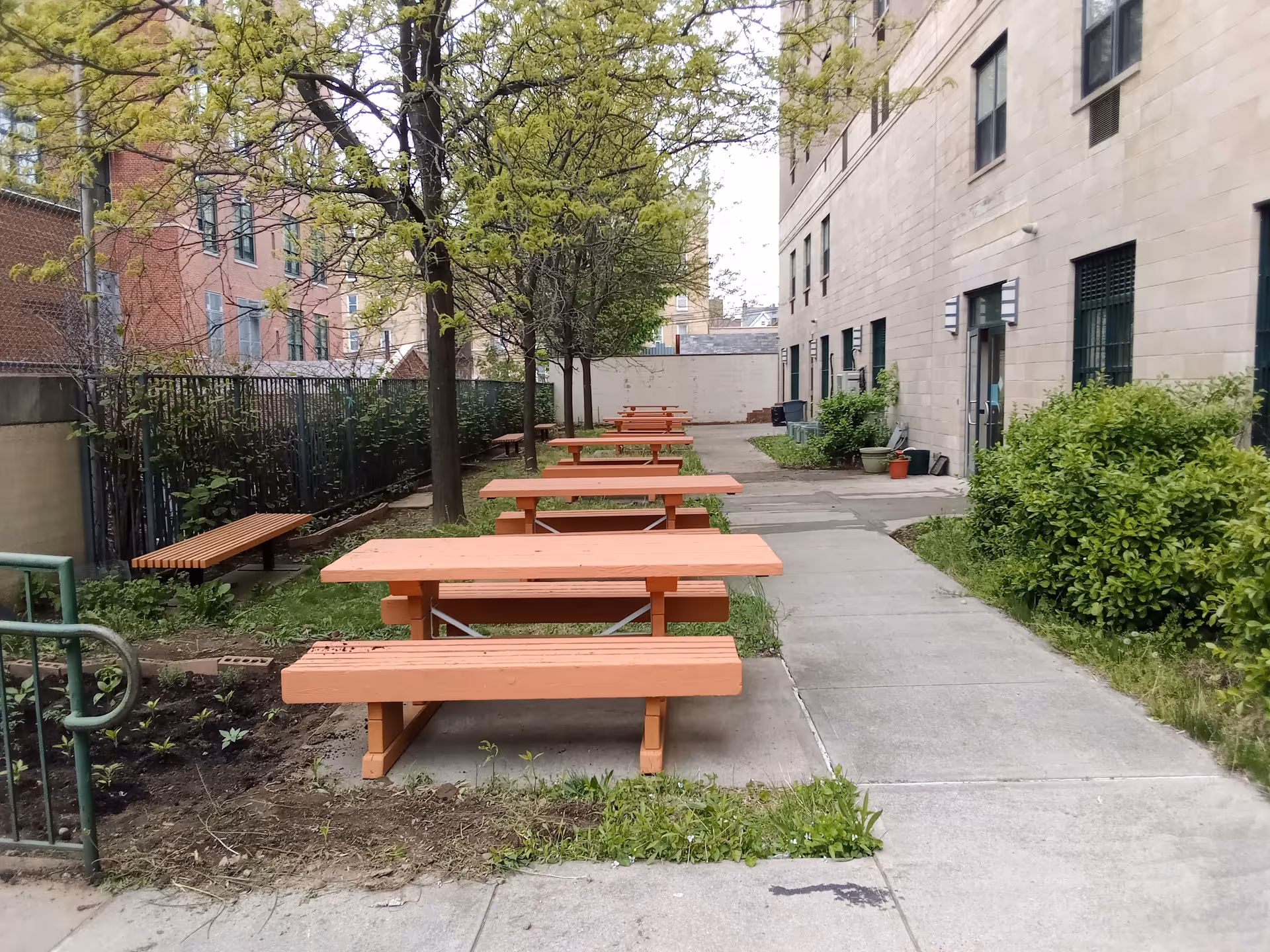 Several orange picnic tables line a walkway in a courtyard.