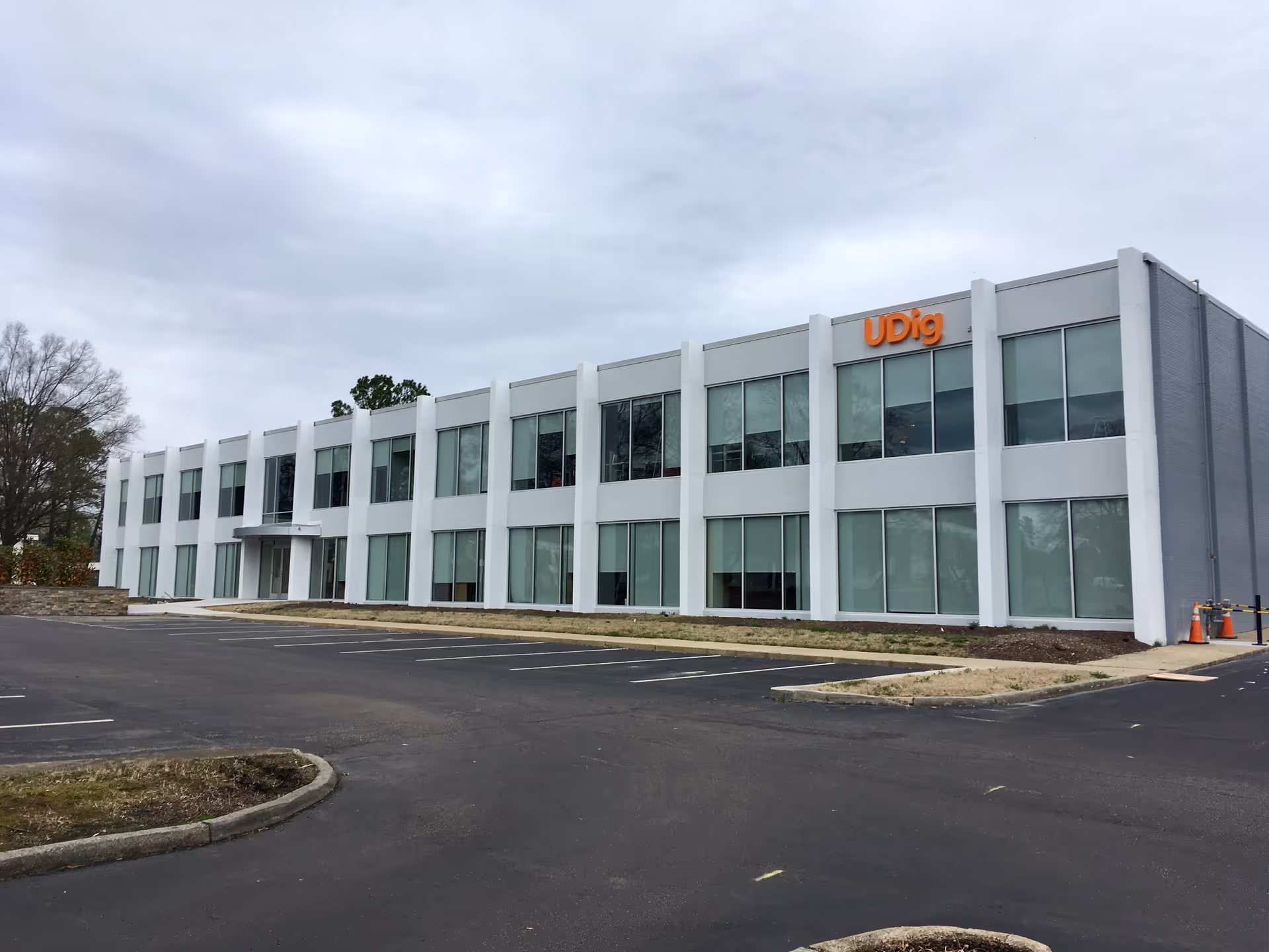 Exterior view of a modern two-story building with large glass windows and an empty parking lot.