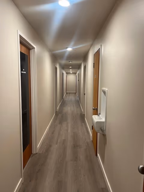 A long, well-lit hallway in a senior living facility with doors along both sides.