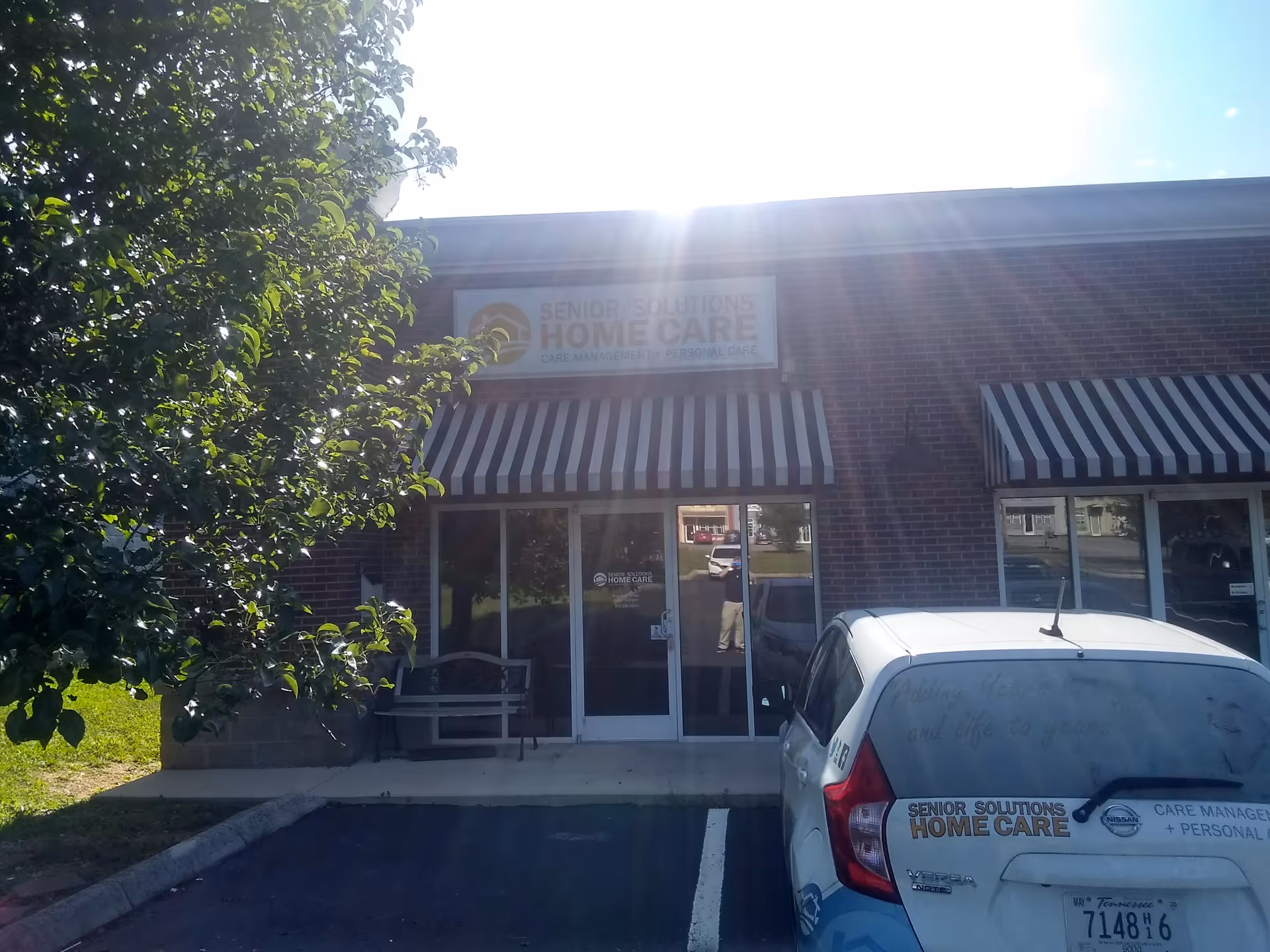 Front view of Senior Solutions Home Care storefront with striped awnings and a parked car