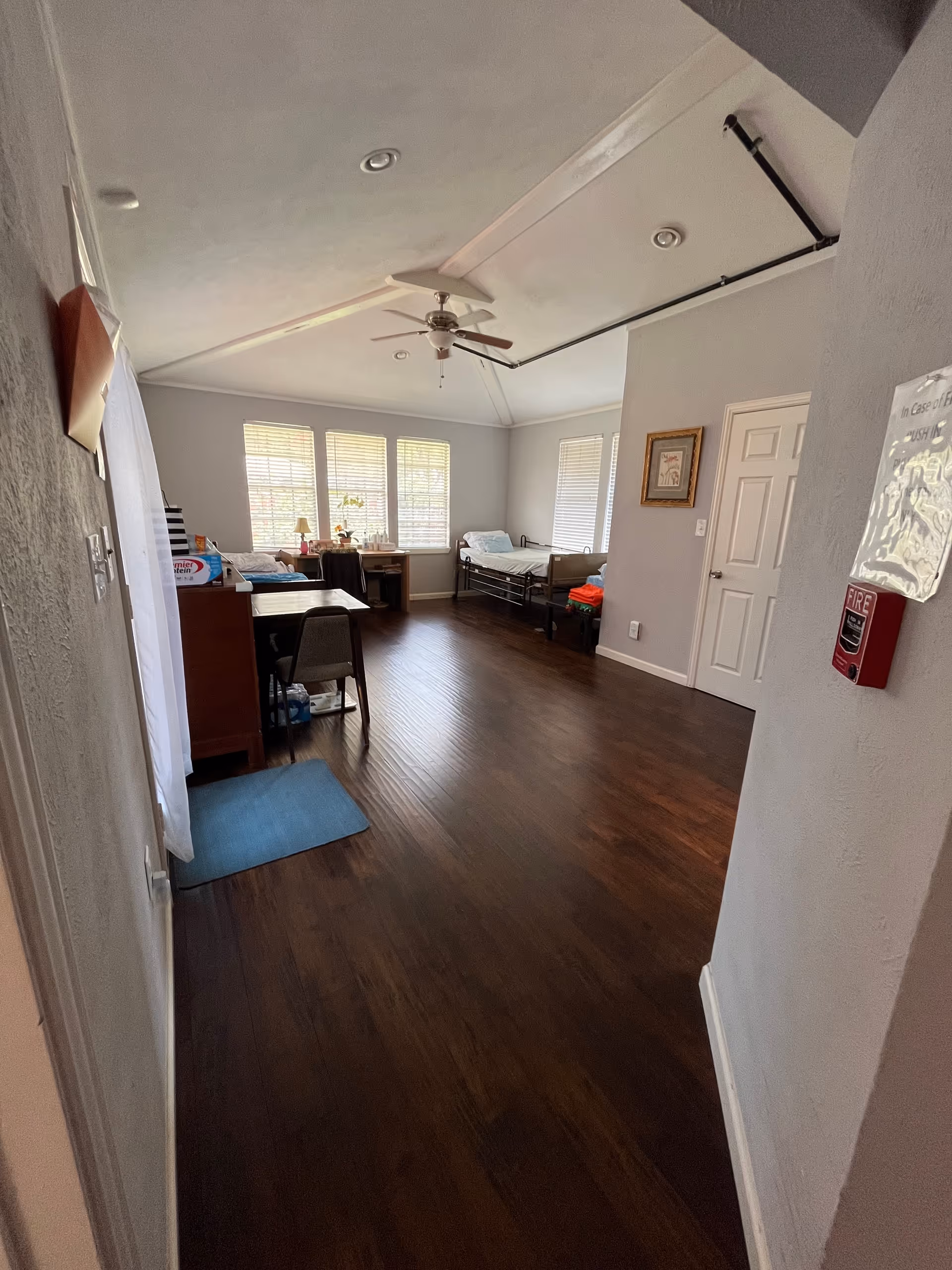 Interior shared living area of Sunny Oak Care Home with beds, desks, and windows.