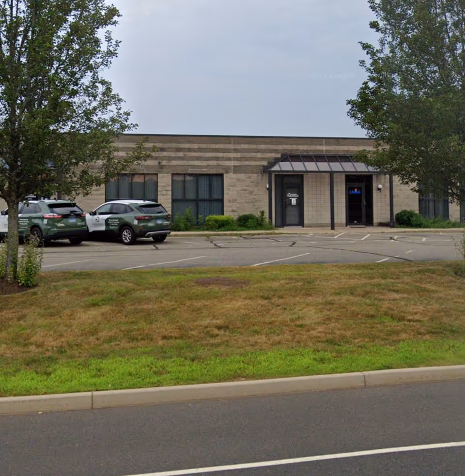 Exterior view of a senior living facility with a parking lot and trees.
