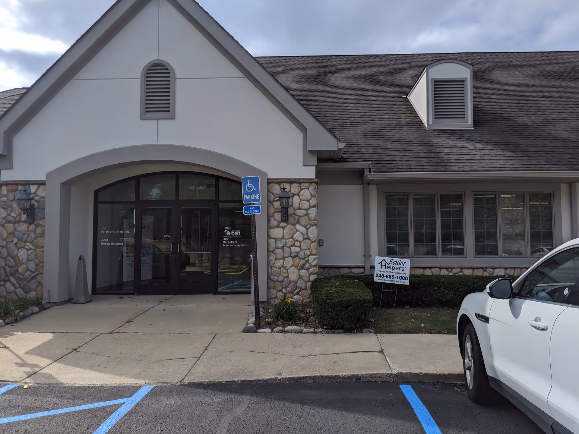 Facade of a Senior Helpers facility with glass entry doors and a handicapped parking sign visible.