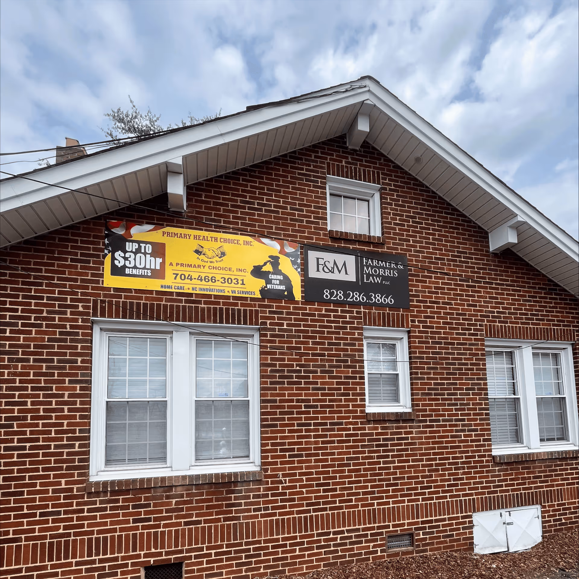 Red brick building exterior with banners for Primary Health Choice and E&M law services.