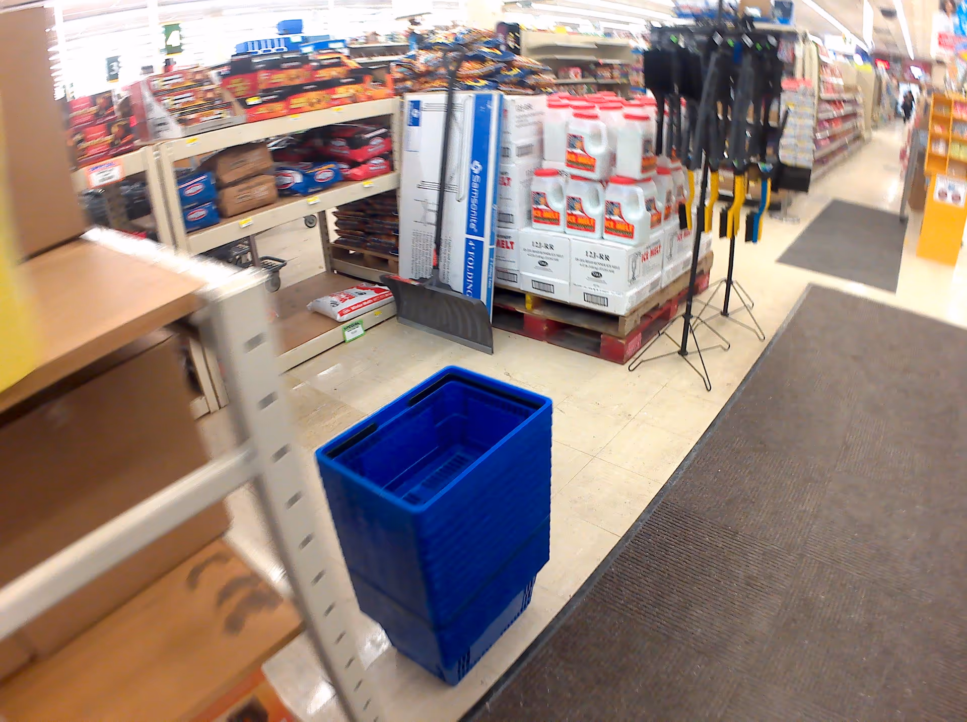 Inside Discount Drug Mart, shelves full of items and a blue plastic bin on the floor.