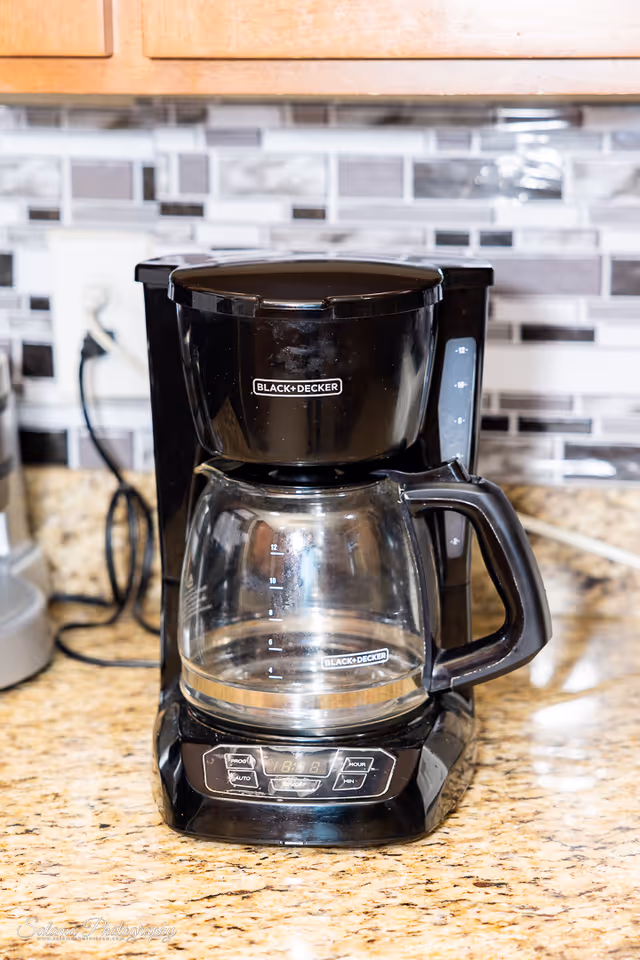 Black+Decker coffee maker on a speckled kitchen counter with tiled backsplash.