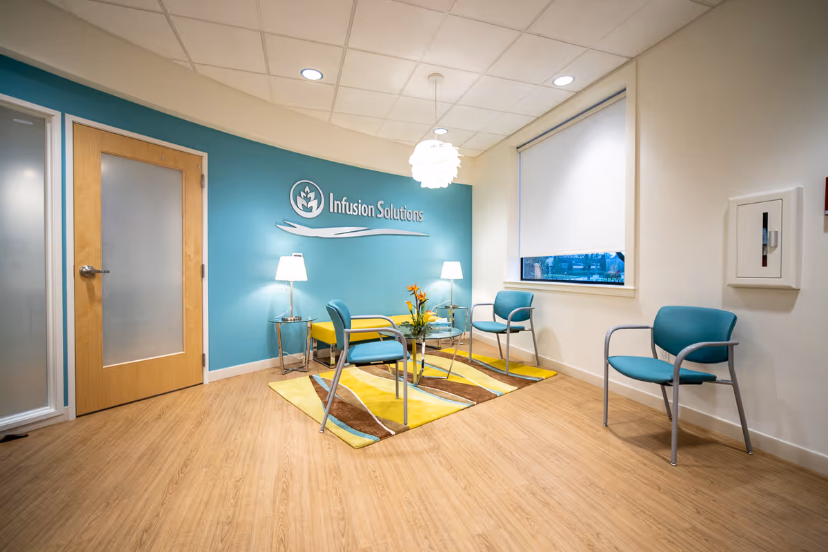 Infusion Solutions lounge area with teal wall, chairs, rug, and reception seating.