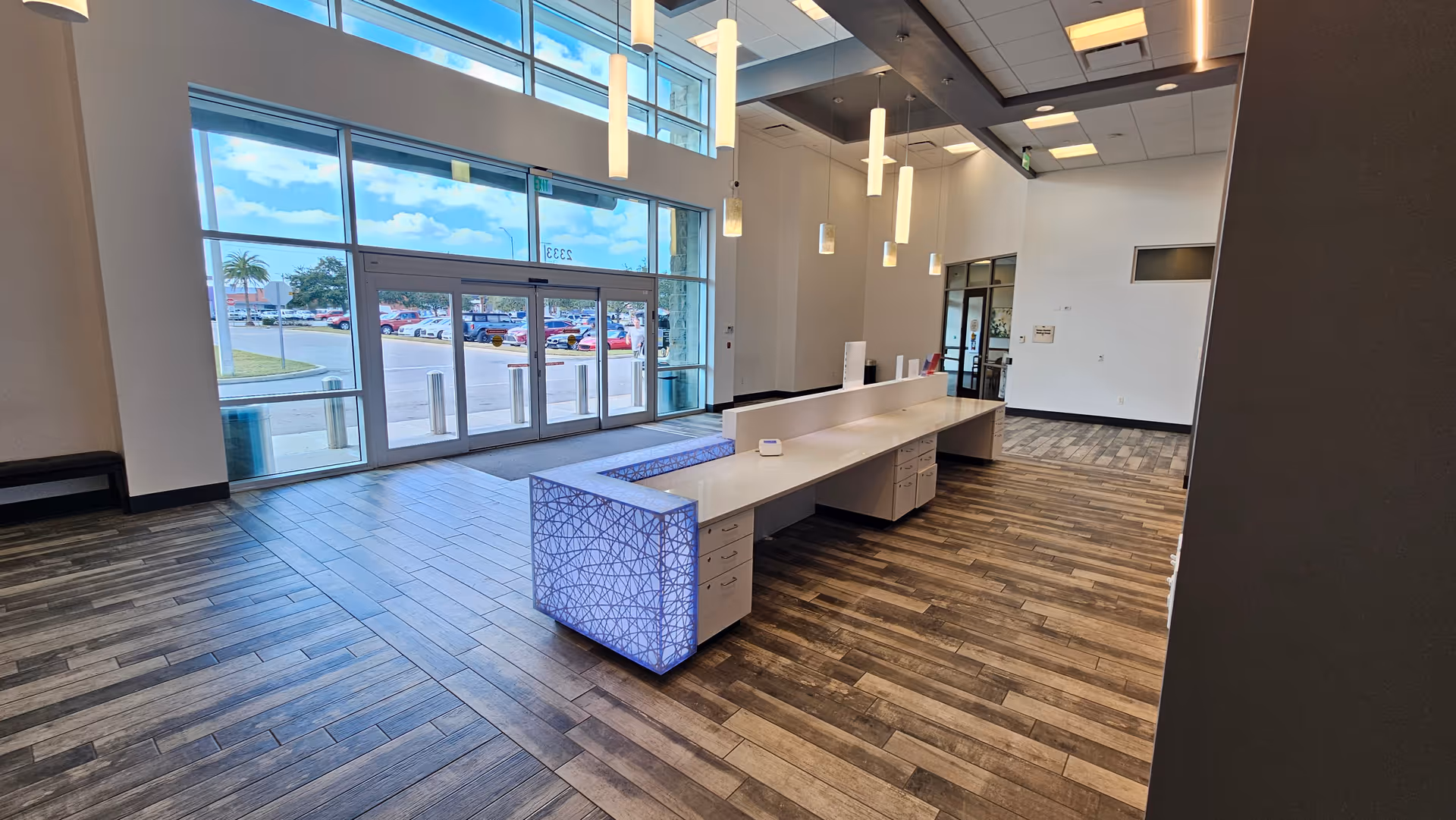 A spacious facility lobby with a long white reception desk and glass doors.