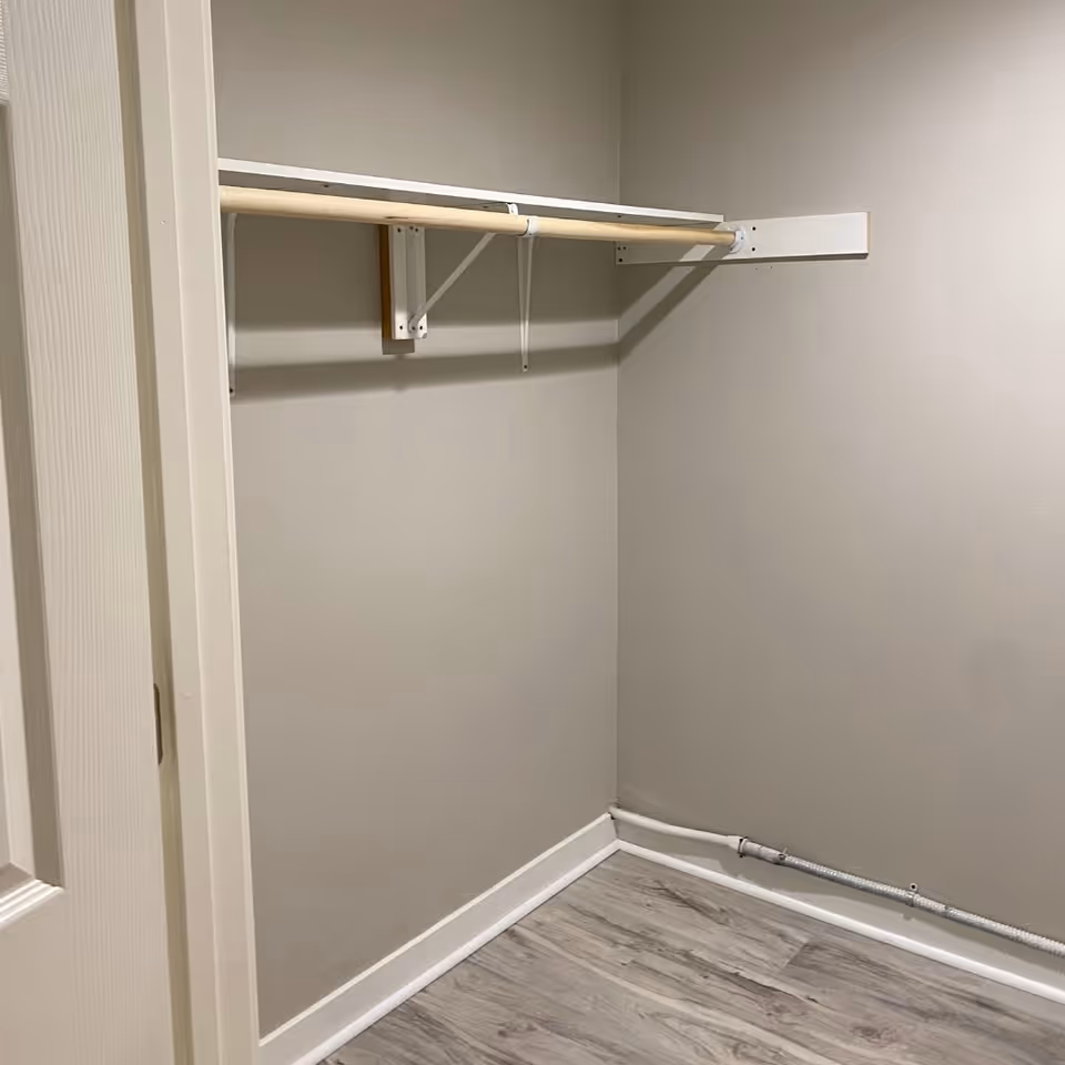 Empty closet with a rod and shelf in neutral-toned interior.