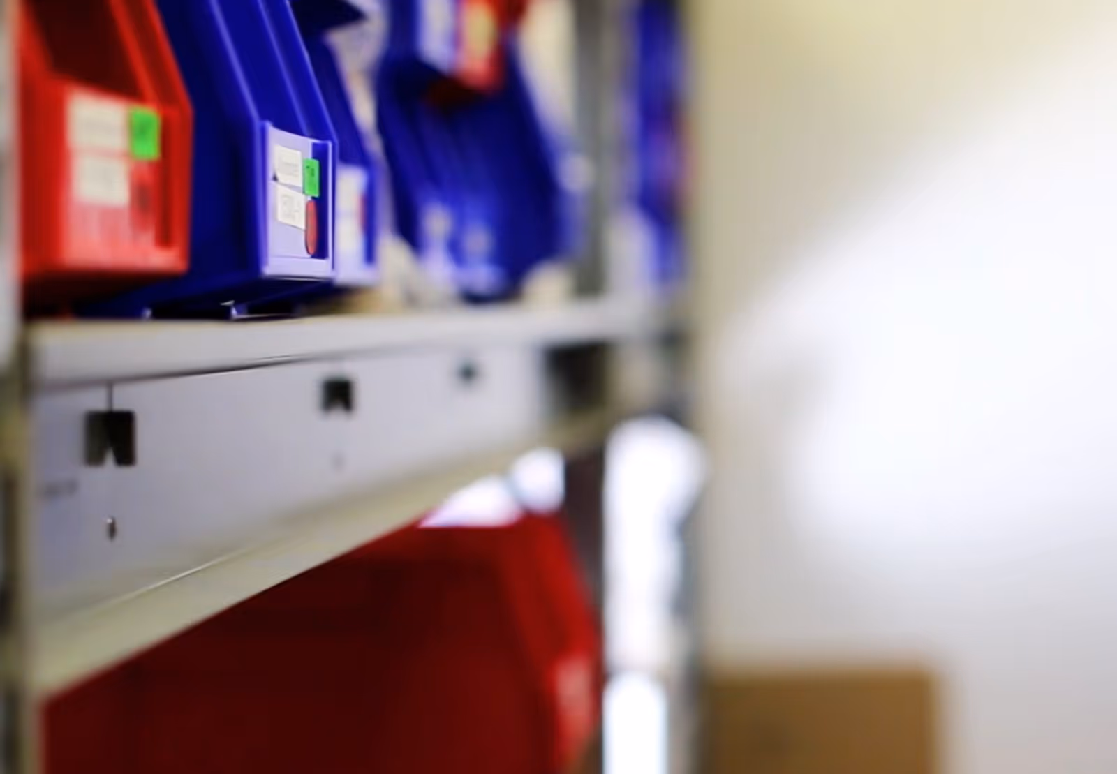 Rows of colored plastic bins on metal shelving in a storage closet.