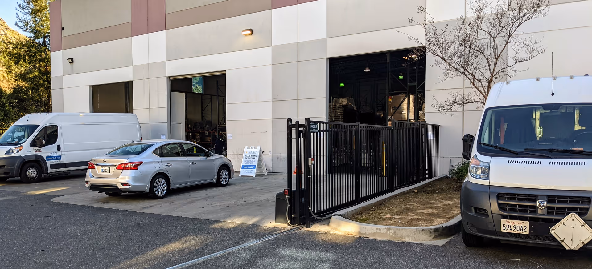 Building exterior of a facility with a gated driveway and parked vans.