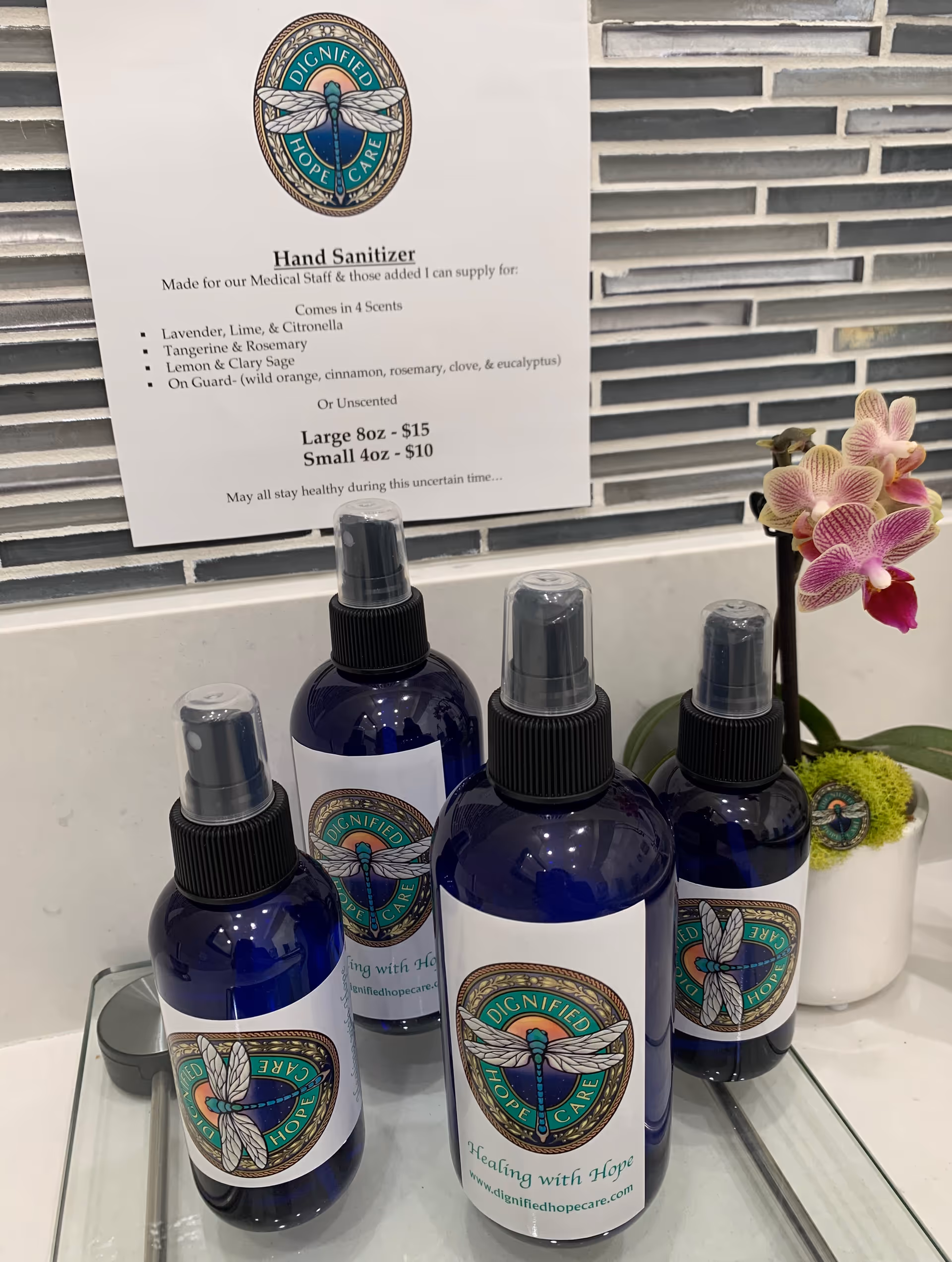Blue hand sanitizer bottles sit on a counter beside a Dignified Hope Care sign.