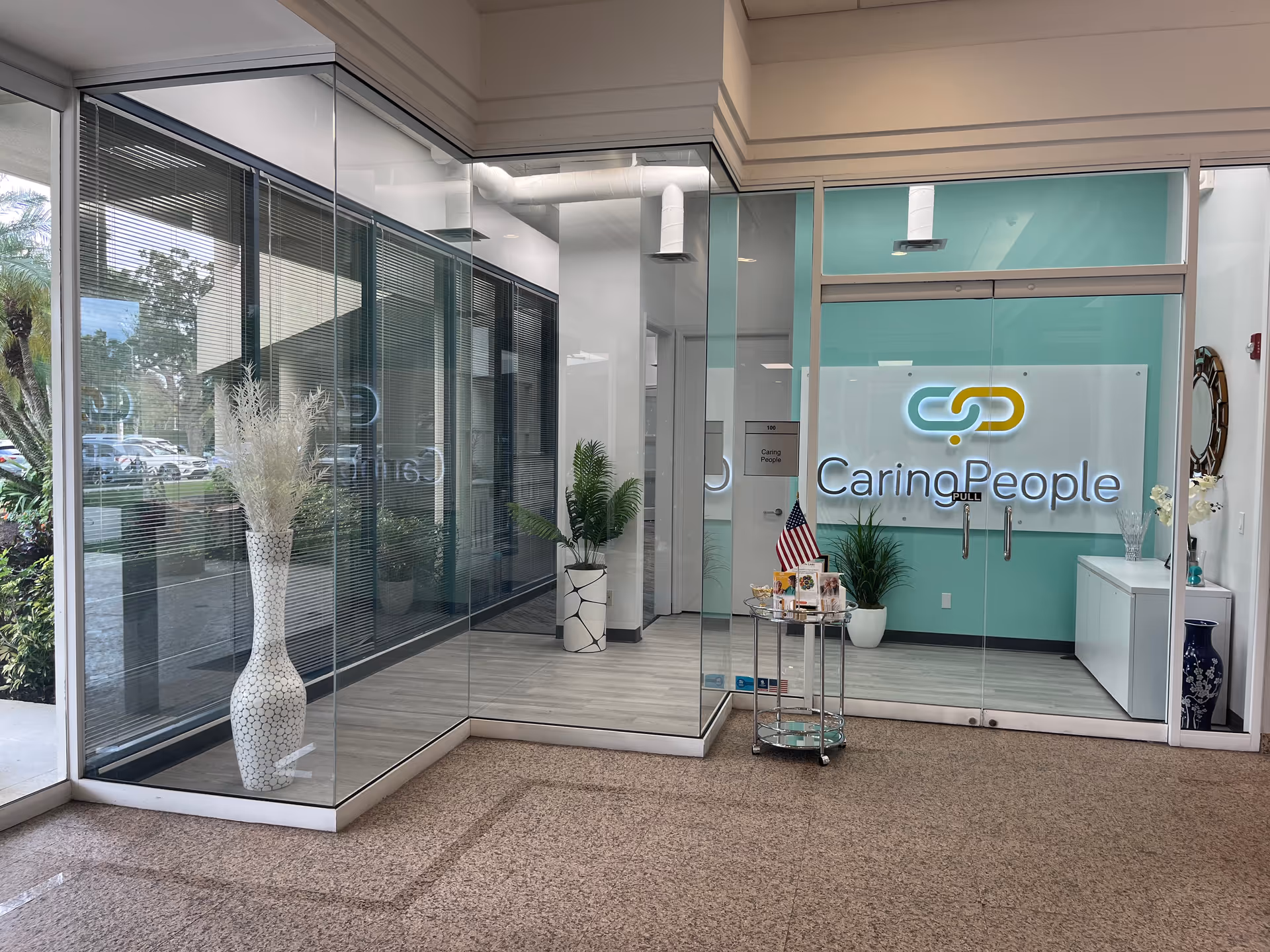 Glass-walled lobby with Caring People sign and reception desk.