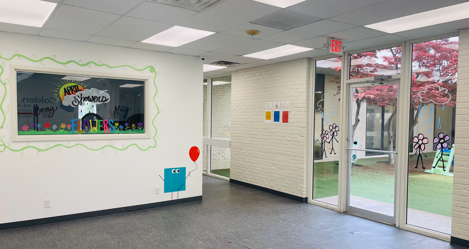 Indoor hallway of a senior living facility with glass doors and bright art.
