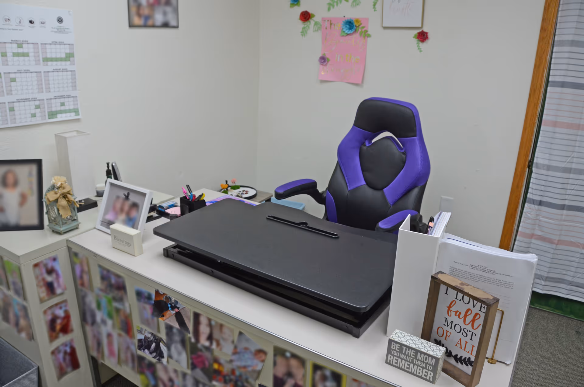 Office desk with a purple-and-black chair and photos on cabinets.