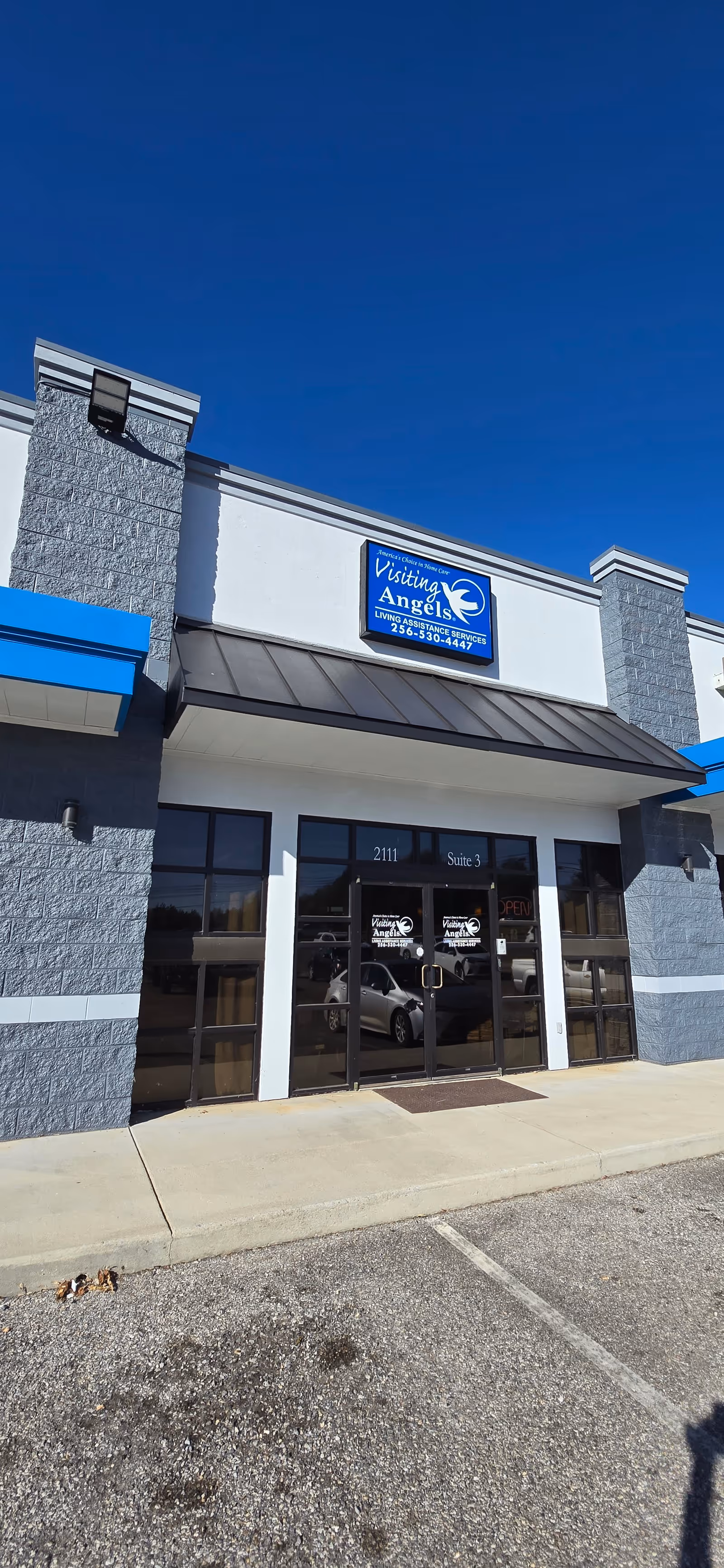 Exterior view of Visiting Angels Senior Home Care storefront with glass doors and blue signage.