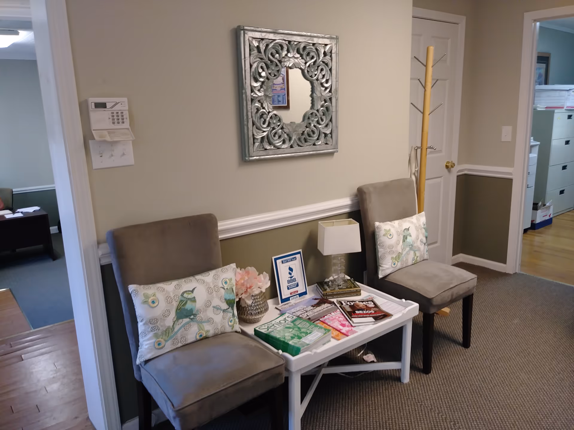 Two chairs with cushions surround a small table with magazines in a waiting area.