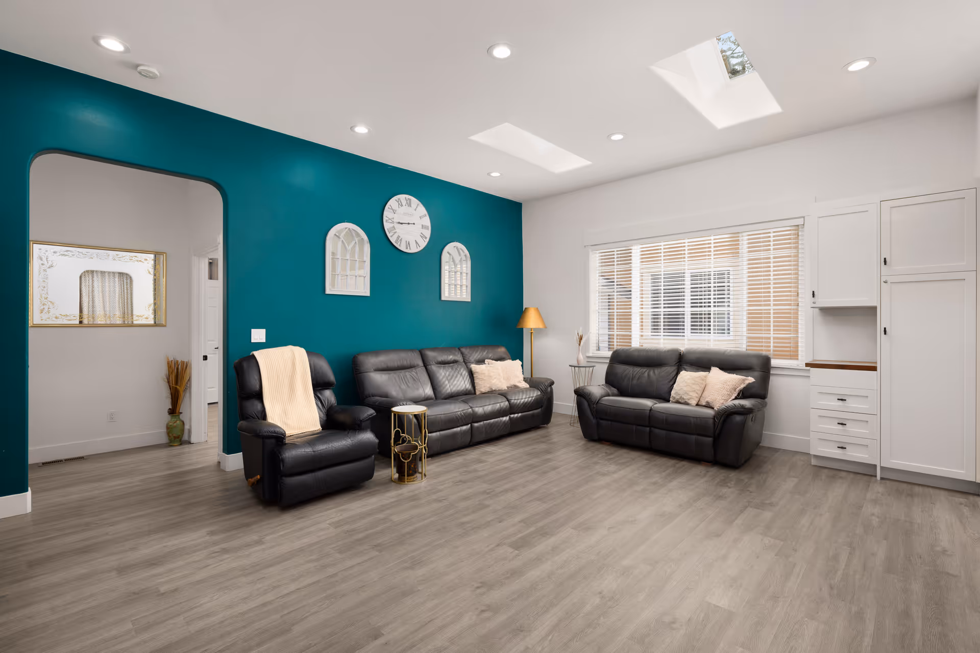 Bright living room at Lake Hills Living, AFH with teal wall, leather sofas, and skylights.