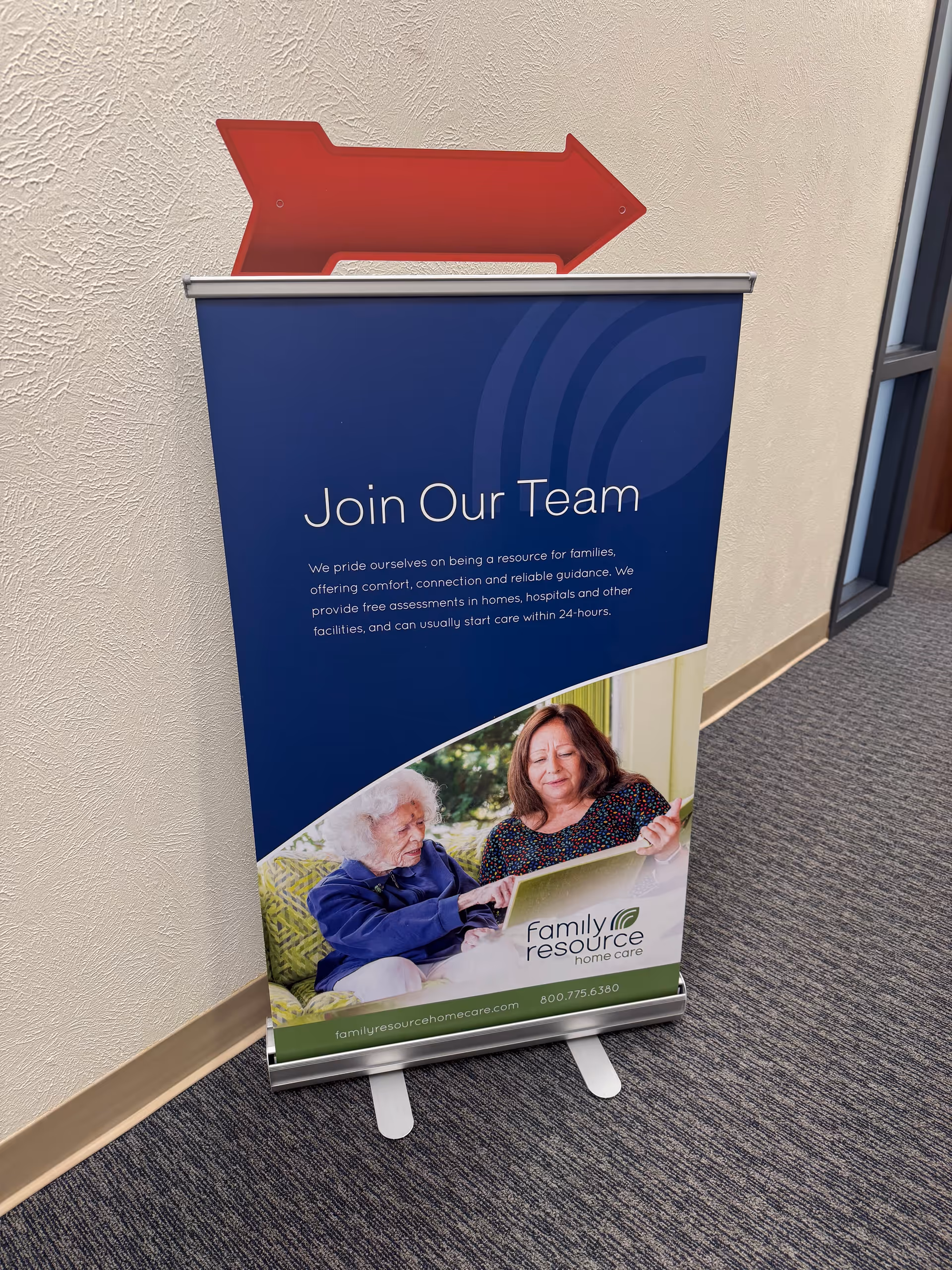 Blue promotional banner in hallway reads 'Join Our Team' featuring two people.