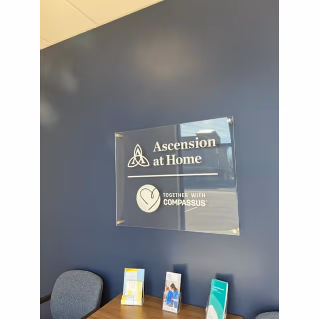 Interior lobby wall displaying Ascension at Home sign with Compassus branding and brochures.