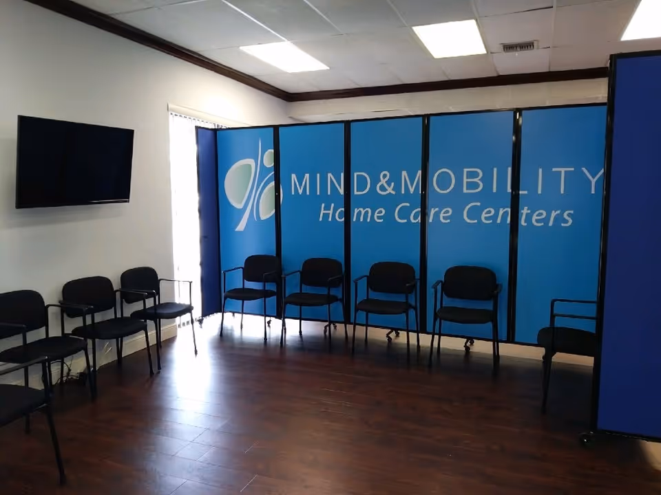 Waiting area with blue partition displaying Mind & Mobility and row of black chairs.