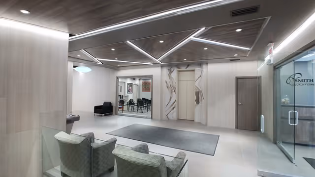 Modern, well lit senior care lobby with chairs, rug, glass walls, and a meeting room.