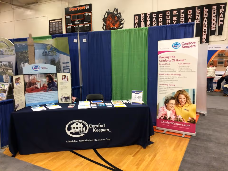 Trade show booth for Comfort Keepers in home care with table, banners, and brochures.