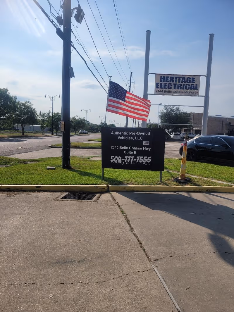 Outdoor street scene with American flag and business signs along a roadway.