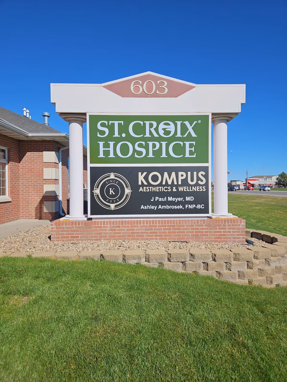 Exterior view of a St. Croix Hospice sign on a brick pedestal in front.