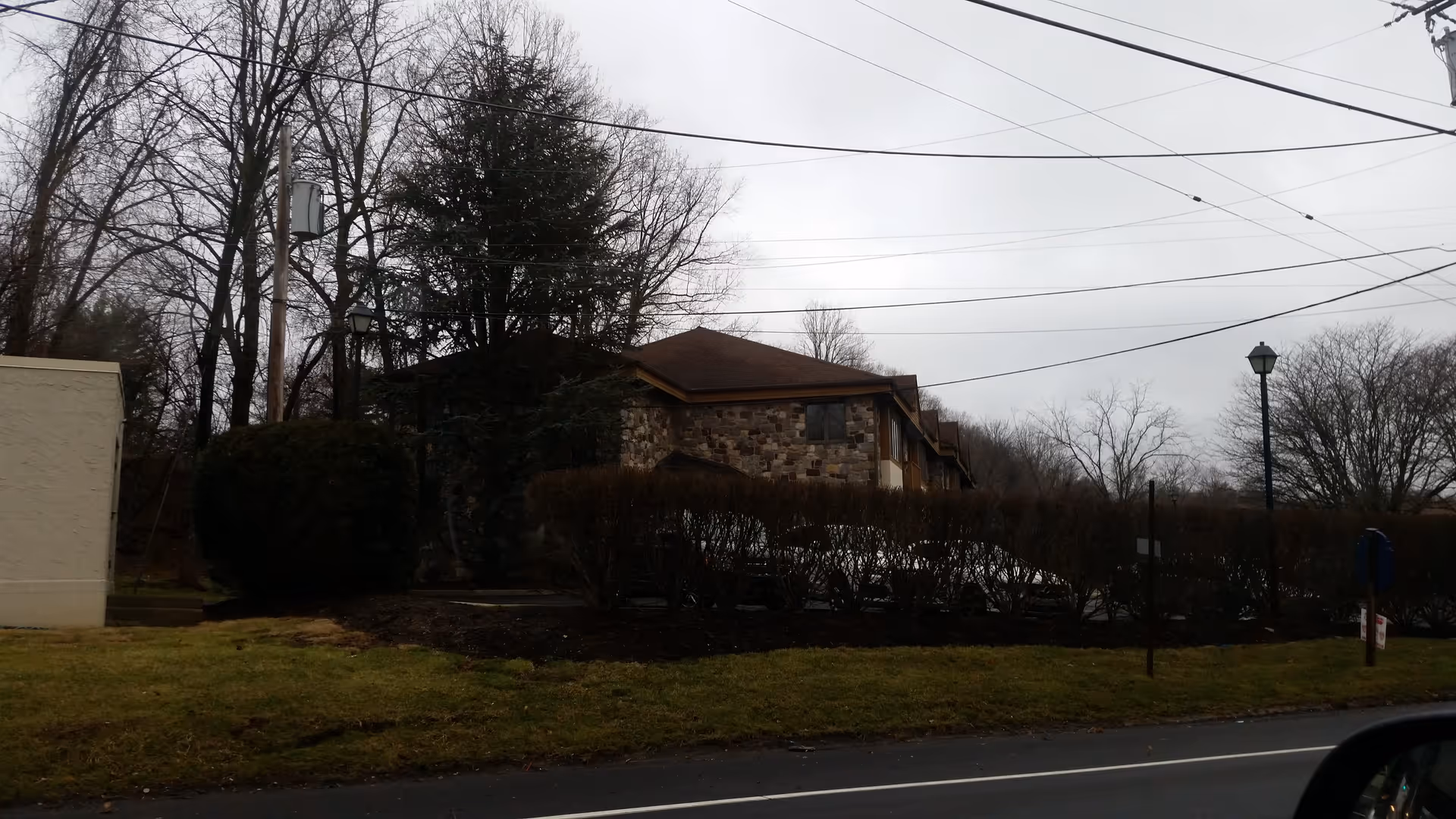 Exterior view of a BrightStar Care facility behind hedges along a street.